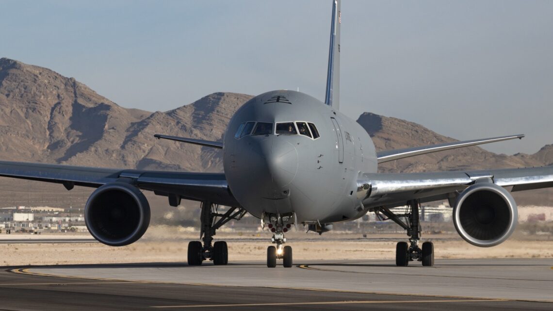 KC-46A na ziemi, widziany od nosa, w tle góry